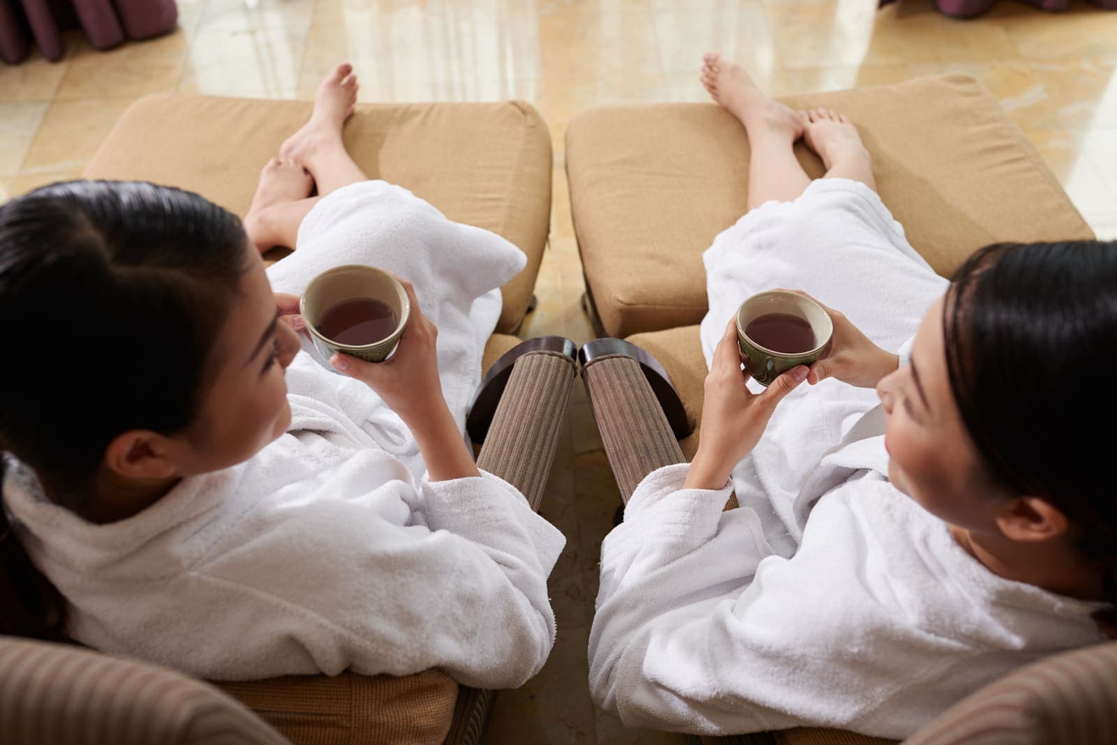 Two guests in soft robes sharing tea in the RISE lounge