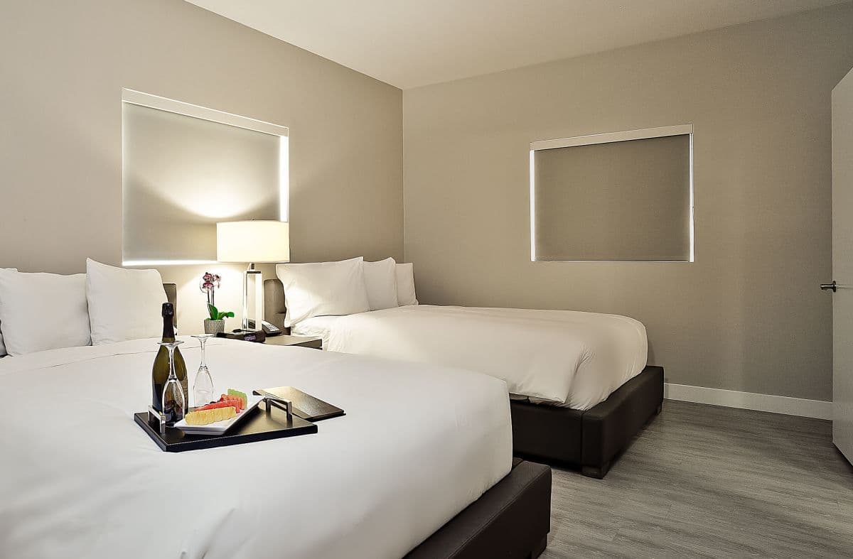 A guest room at The Grand Hotel with white linens, warm neutral walls, and a wood floor