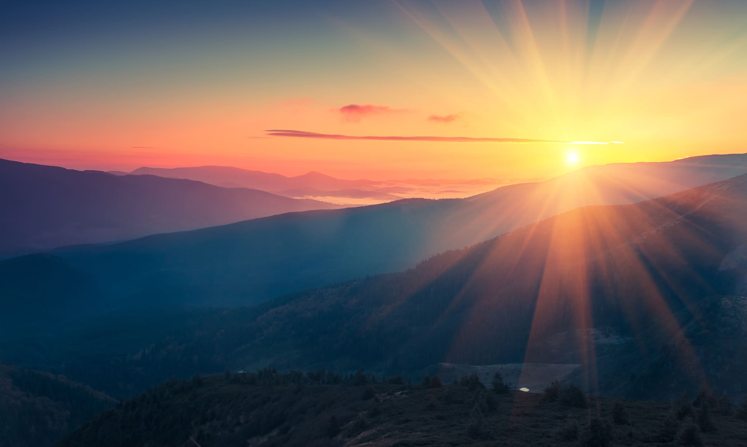 The sun rising over misty blue mountain ridges